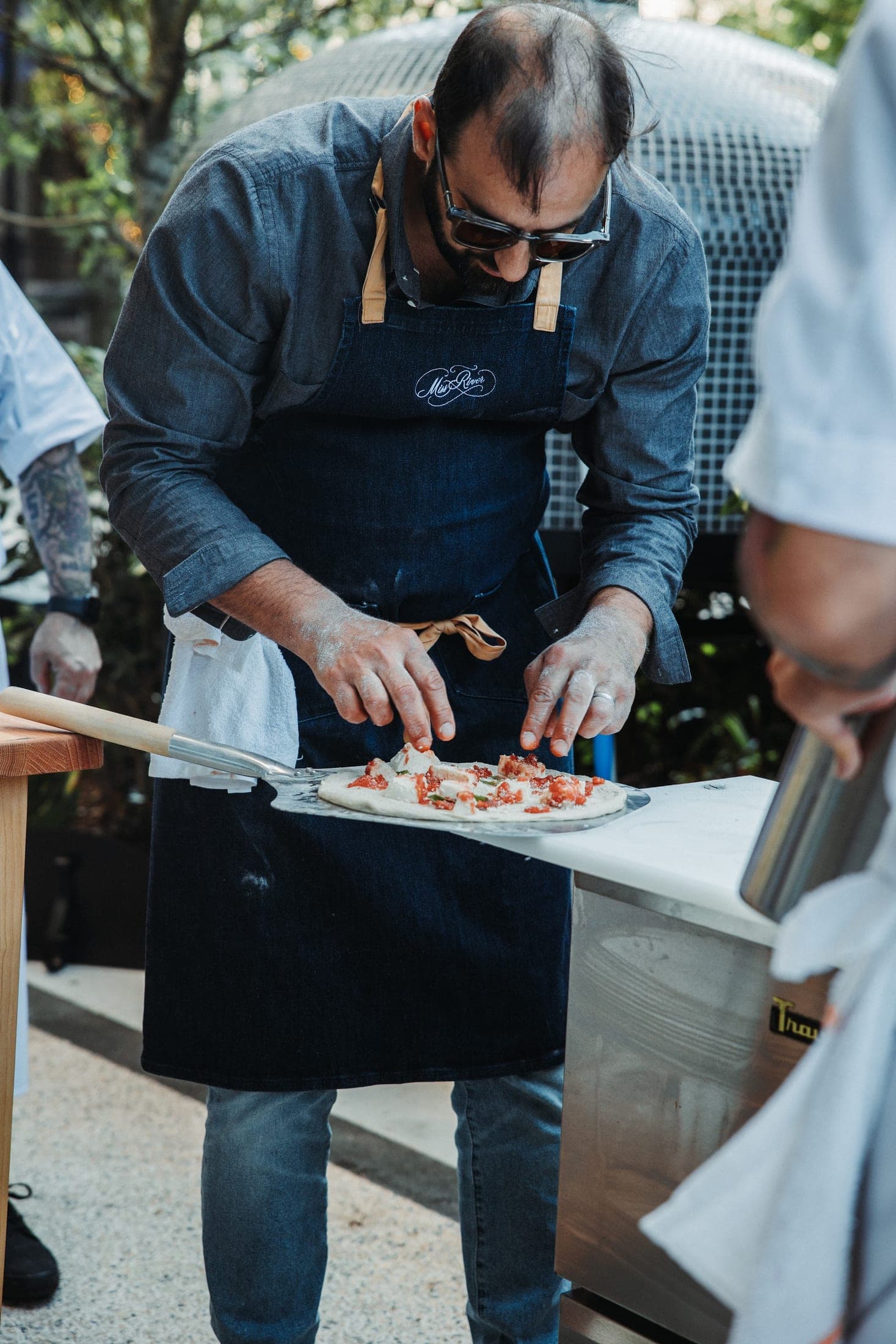 A chef firing a wood-oven pizza